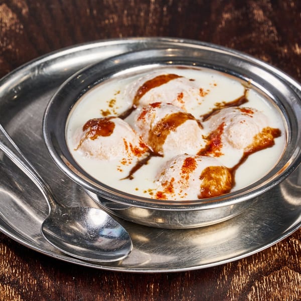 Dahi Vada, an Indian dish with lentil fritters in yogurt, drizzled with tamarind chutney and spices.